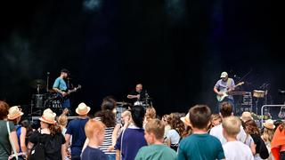 Eine Band steht auf einer Bühne. Davor sind Zuschauer zu sehen. (Foto: Dirk Guldner)