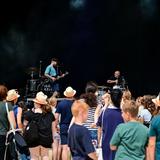 Eine Band steht auf einer Bühne. Davor sind Zuschauer zu sehen. (Foto: Dirk Guldner)