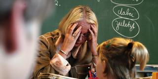 Eine Lehrerin stützt am Pult den Kopf auf die Hände (Foto: IMAGO / photothek)