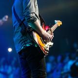 Ein Mann steht auf einer Bühne vor Publikum und spielt Gitarre  (Foto: pixabay.com)