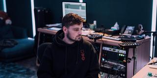 Martin Garrix sitzt in einem Studio und schaut seitlich auf einen Bildschirm. (Foto: Presse)