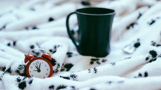 Ein Wecker und eine Tasse auf einer Bettdecke (Foto: pixabay.com/stocksnap)