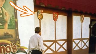 Ein Mann läuft entlang eines Gebäudes. An der Wand hängen Wappen, unter anderem das Saarland-Wappen (Foto: Netflix/Better Call Saul/Folge 10 "Marco")