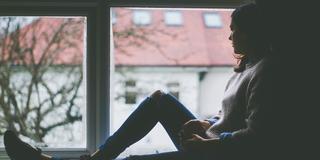 Eine Frau sitzt auf einer Fensterbank und schaut hinaus (Foto: pixabay.com)