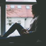 Eine Frau sitzt auf einer Fensterbank und schaut hinaus (Foto: pixabay.com)